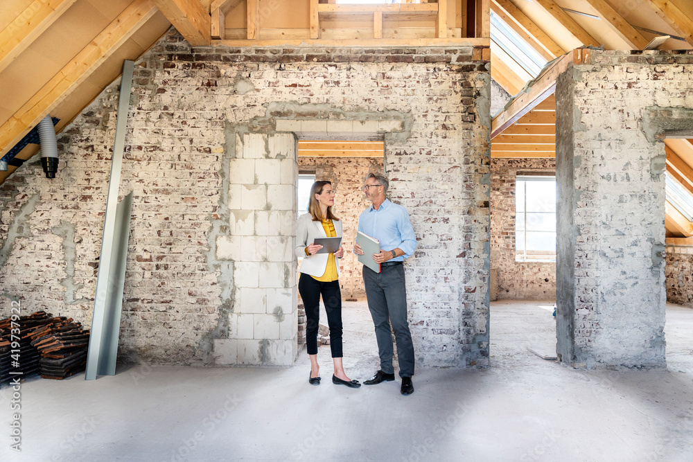 Businesswoman having discussion with expertise while standing at construction site Businesswoman having discussion with expertise while standing at construction site