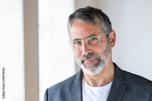 Mature entrepreneur wearing eyeglasses staring while standing at home