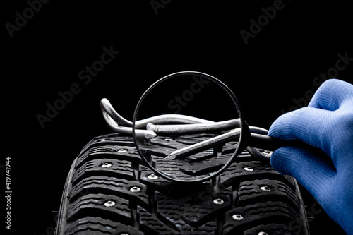 huge nail on a tyre over black background. studio shot. copy space. repair car tire concept. trouble on path conceptual