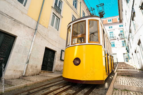 Front view of famous retro yellow Bica funicular tram in narrow streets of Lisbon old town, Portugal