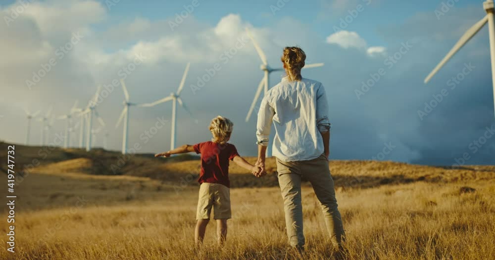 Father and son with windmills on golden hillside at sunset, dreaming of a clean and sustainable future for generations to come, heart warming uplifting picture of clean energy for the environment