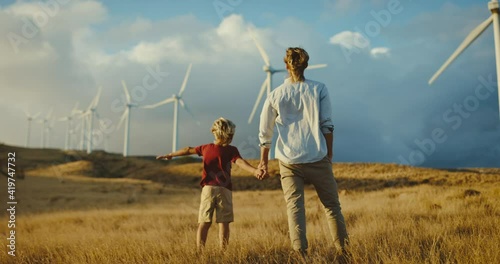 Father and son with windmills on golden hillside at sunset, dreaming of a clean and sustainable future for generations to come, heart warming uplifting picture of clean energy for the environment