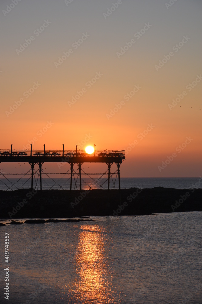 a view of the sun setting behind Aberystwyth pier 