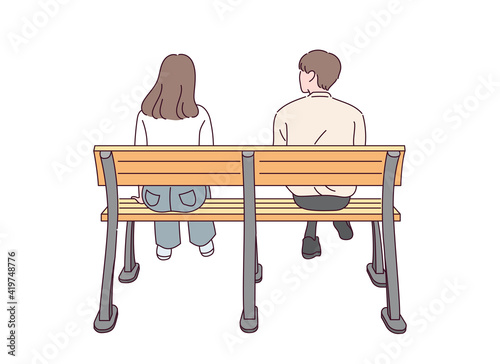 The back view of a male and female couple sitting on a bench.