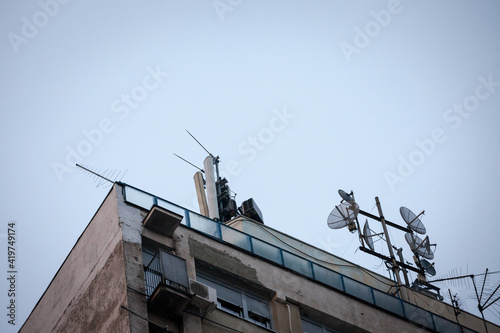 Mobile phone base station, equiped with 3G, 4G and 5G antenna, at the top of a European residential building, used for cellular phone network coverage, reception and transmission