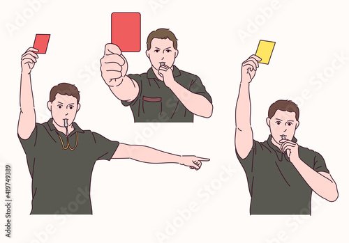 The soccer referee is holding a red and yellow card and blowing a whistle.