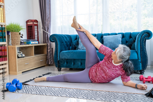 Portrait healthy senior woman exercise with side-lying leg lift photo