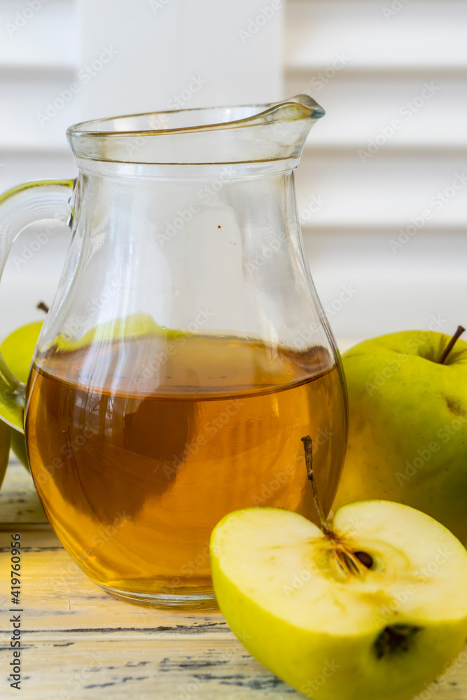 Green apples and jug with apple juice on wooden background Green apples and jug with apple juice on wooden background