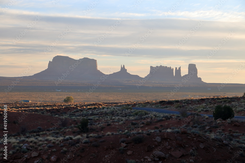 First rays of morning sun shine on the landscape at Monument Valley, Arizona