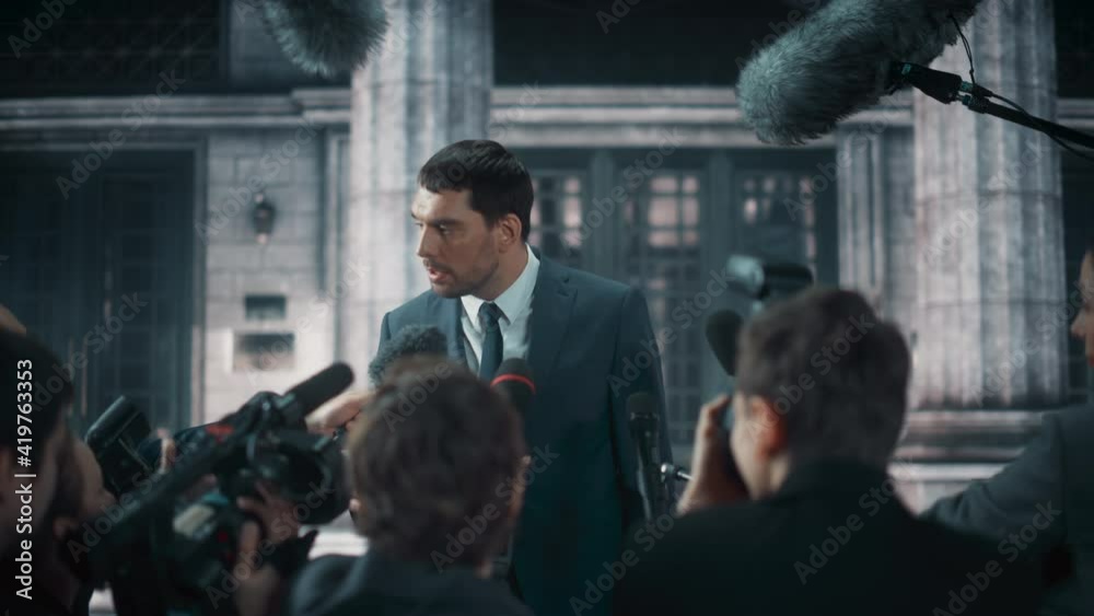 Young Organization Representative Answering Press Questions and Giving Interview Outside a Parliament, Court or Other Government Building. Press Officer or Businessman Crowded by News Journalists. Young Organization Representative Answering Press Questions and Giving Interview Outside a Parliament, Court or Other Government Building. Press Officer or Businessman Crowded by News Journalists.
