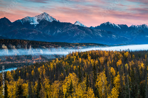 dramatic autumn sunrise in the snow capped Chugach mountain range and Matanuska river in Alaska.