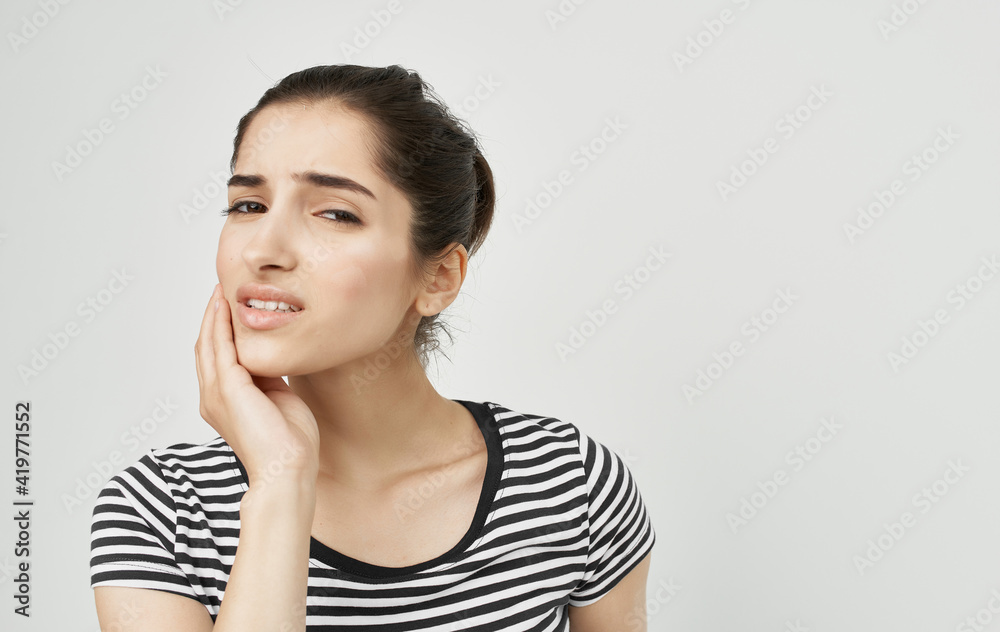 woman in striped t-shirt holding face dental problems pain discontent woman in striped t-shirt holding face dental problems pain discontent