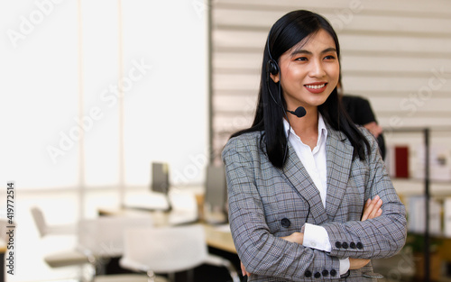 Portrait close-up shot of young pretty confident happy successful asian businesswoman operator wear gray stripe suit stand smiling cross arms in front of male female colleagues in blurred background
