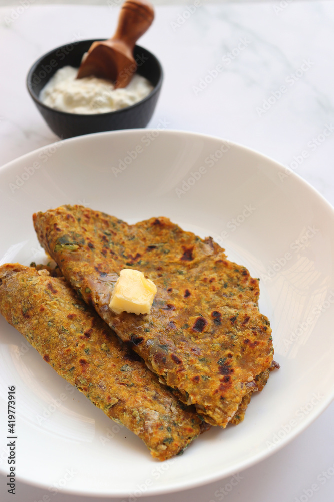 Radish or Mooli masala Paratha served on a white plate with butter cubes. Served with curd, pickle, and green chili. copy space. Muli ke parathe. Radish masala roti. Radish or Mooli masala Paratha served on a white plate with butter cubes. Served with curd, pickle, and green chili. copy space. Muli ke parathe. Radish masala roti.