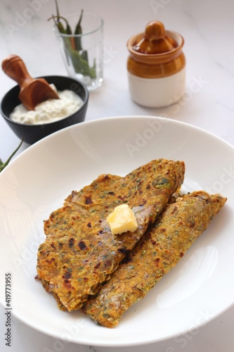 Radish or Mooli masala Paratha served on a white plate with butter cubes. Served with curd, pickle, and green chili. copy space. Muli ke parathe. Radish masala roti.
