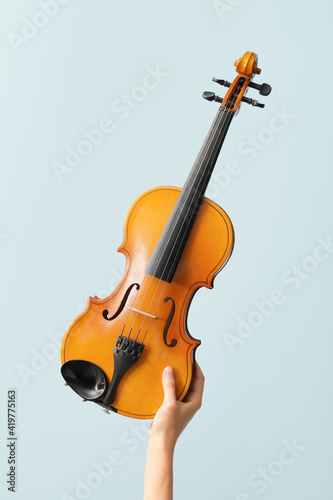 Woman holding violin on color background
