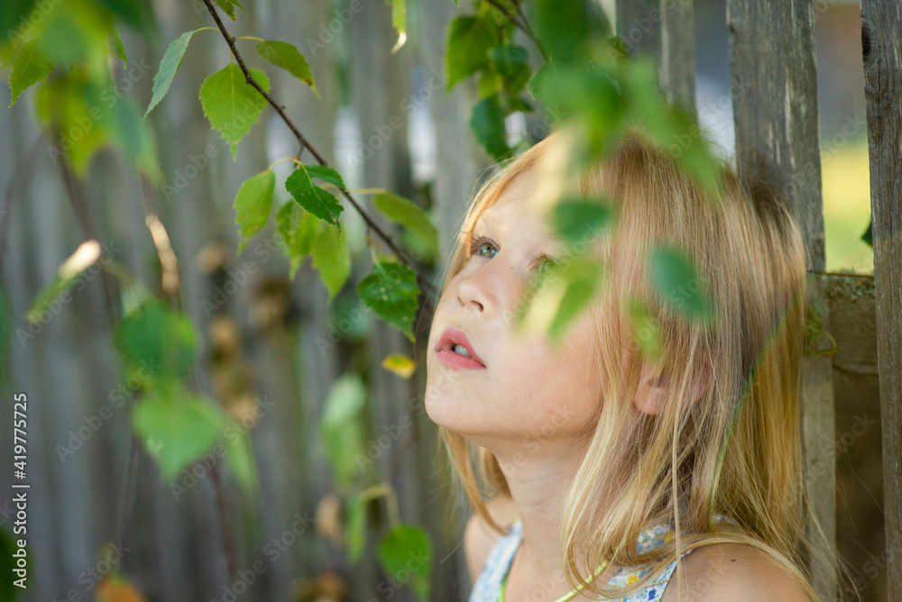 blonde girl portrait in green foliage, selective focus blonde girl portrait in green foliage, selective focus