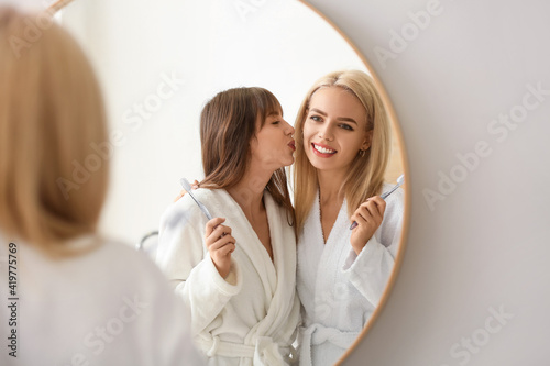 Happy lesbian couple brushing teeth in bathroom