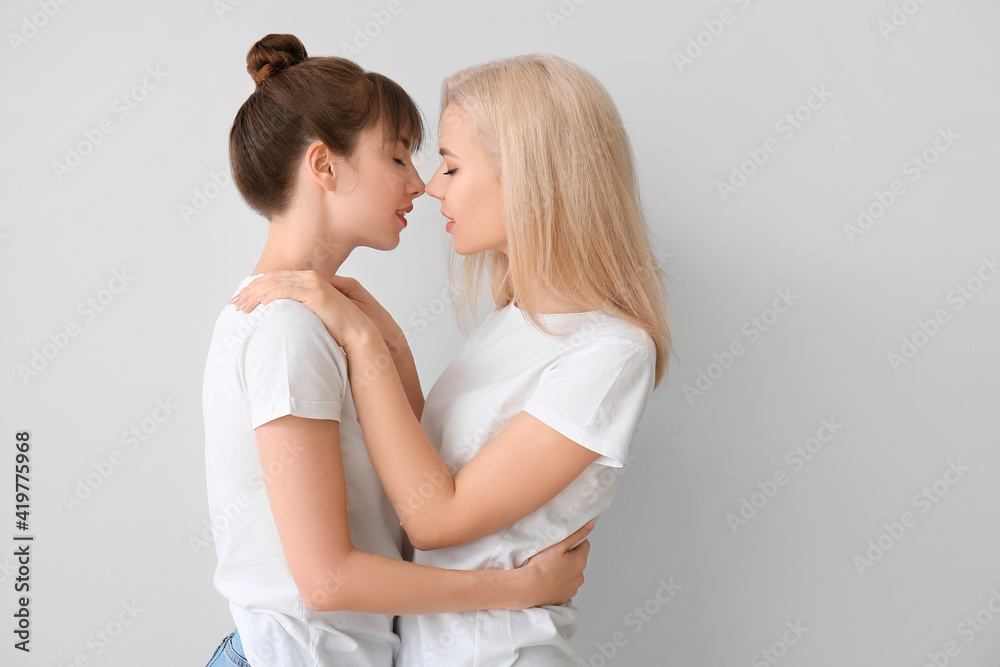 Young lesbian couple on grey background Young lesbian couple on grey background