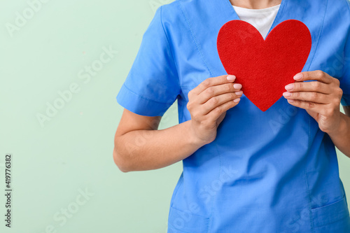 Fototapeta Naklejka Na Ścianę i Meble -  Cardiologist with red heart on color background