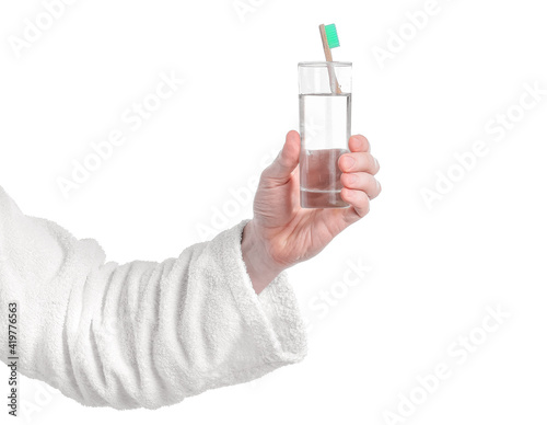 Hand with glass of water and tooth brush on white background