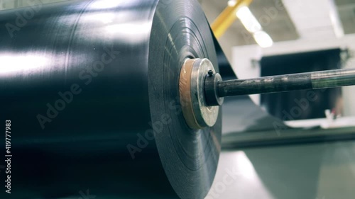 Large roll of black plastic sheeting in a close up. Plastic production, polymer recycling factory.
