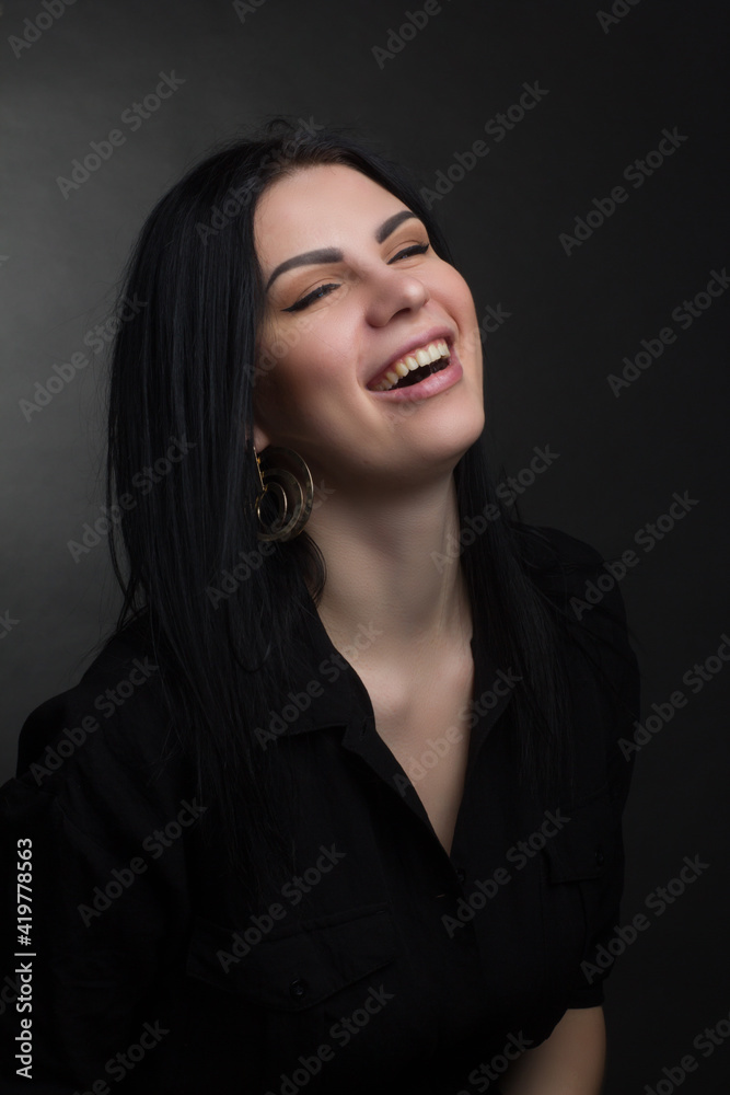 Studio portrait of a brunette in black clothes on a dark background