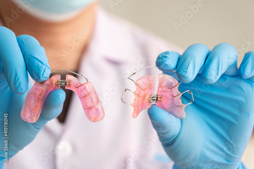 Dentist in rubber gloves is holding a dental device Removable braces for children with crooked teeth