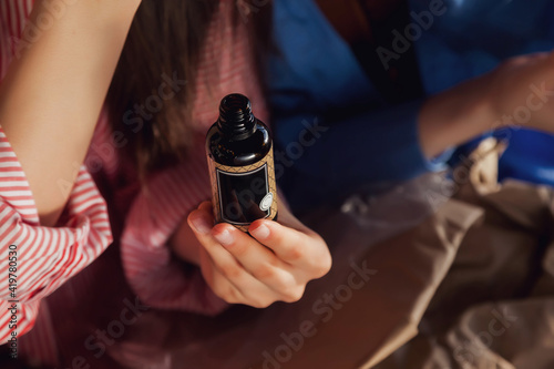 Woman hands holding massage or cosmetics oil bottles. Close up essential oil on chair. High angle view of massage oil bottle on background. Concept of healthy lifestyle and self care. Copy space