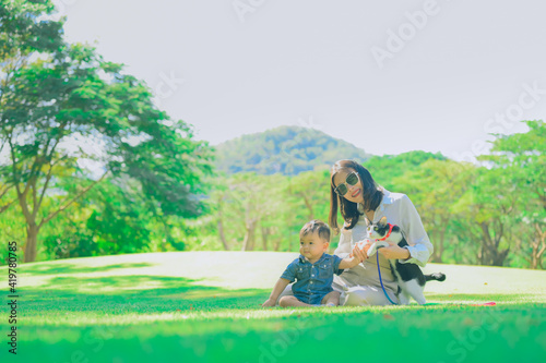 Asian mother and her son playing with their cat at park