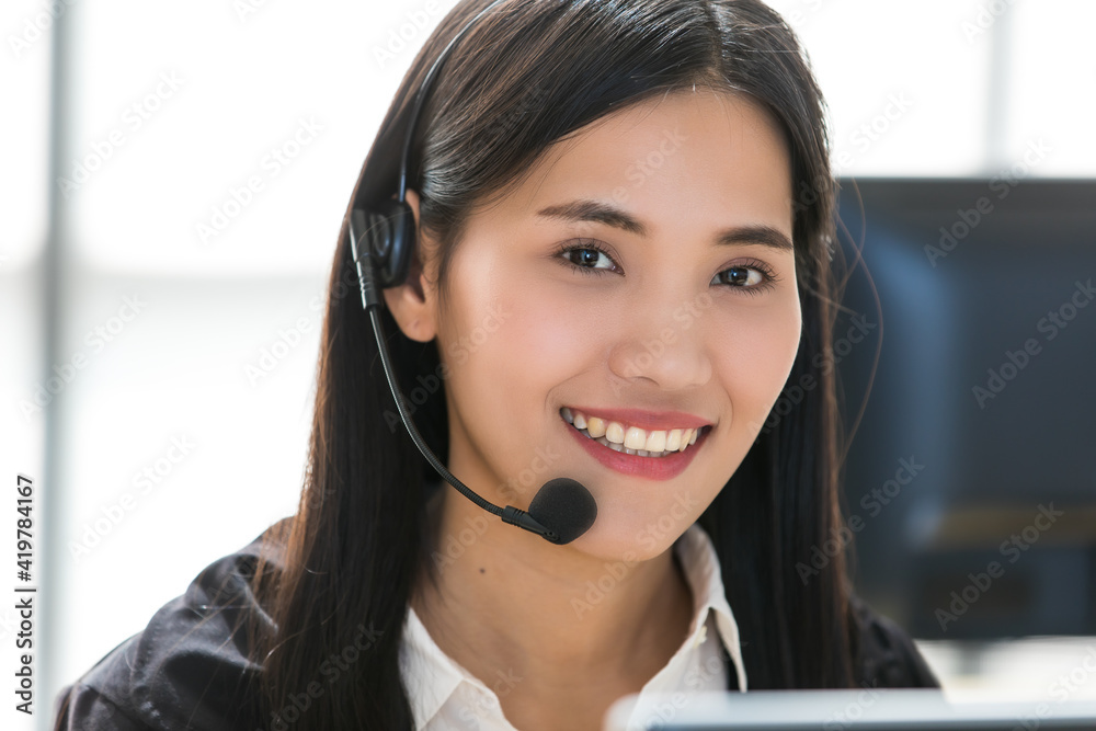 Young and beautiful Asian woman call center officer wearing microphone headset and happy working with a friendly face and positive service mind Young and beautiful Asian woman call center officer wearing microphone headset and happy working with a friendly face and positive service mind
