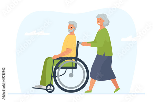 An elderly woman rolls her disabled husband in a wheelchair. A walk and a pastime of a mature married couple.