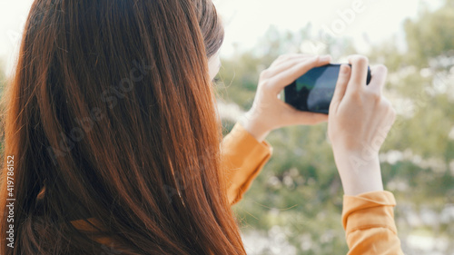 woman outdoors with a phone in her hands taking pictures of nature panorama rest