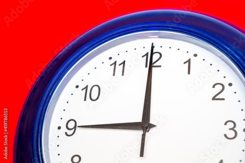 clock on blue, Clock with a blue frame on a red background, nine o'clock on the dial.
