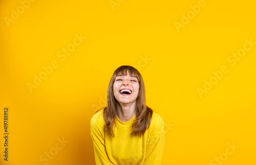 Portrait of happy young woman smiling at camera isolated on bright yellow background © Davide Angelini