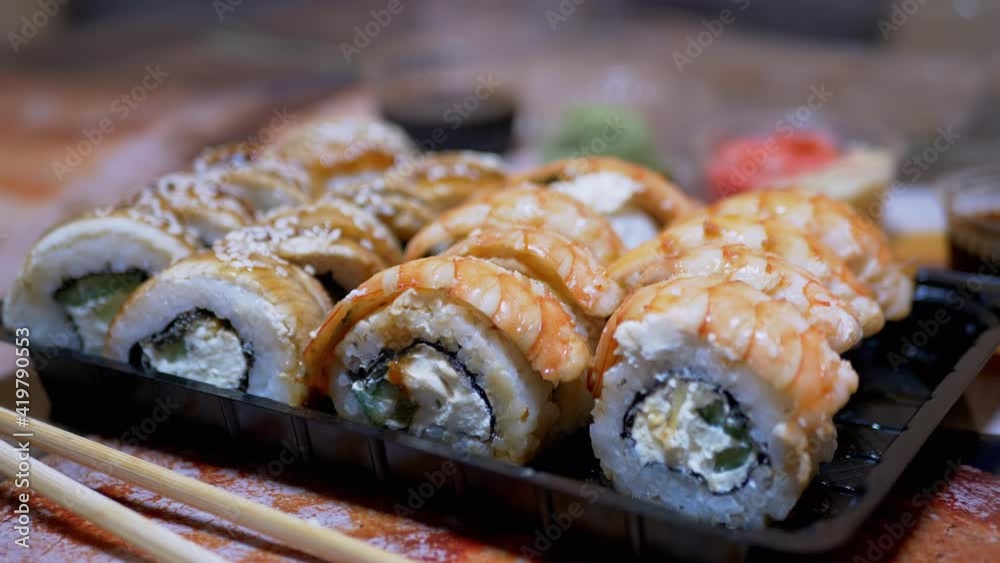 Japanese Sushi Rolls in Plastic Box are Served at Restaurant Table. 4K. Close-up