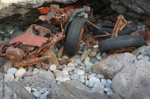 destroyed car parts and wheels in the rocks by the beach in La R  union  France