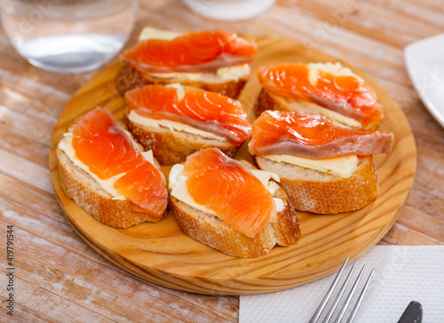 Sandwiches with butter and salted salmon on wooden board. Tasty seafood appetizer