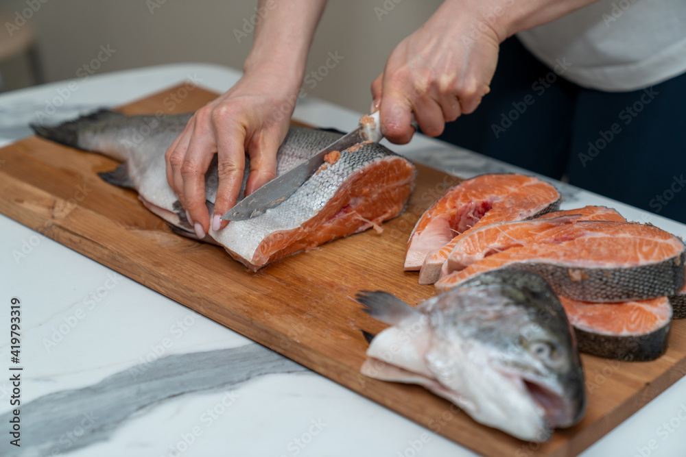 butchering a large trout on a board with a kitchen knife