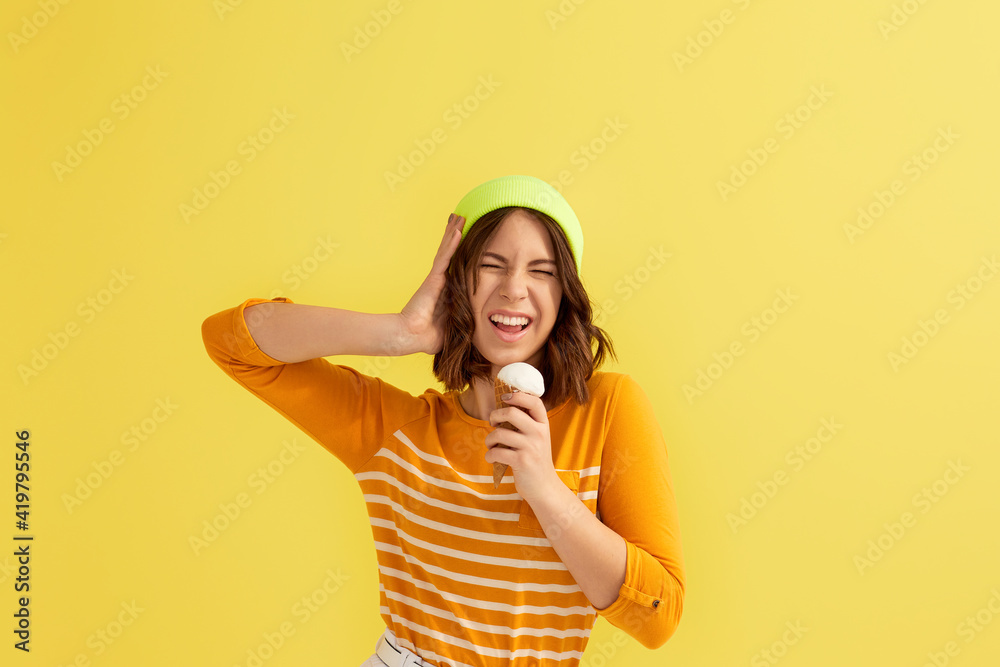 super excited young woman with vanilla ice cream in waffle cone on yellow background. super excited young woman with vanilla ice cream in waffle cone on yellow background.
