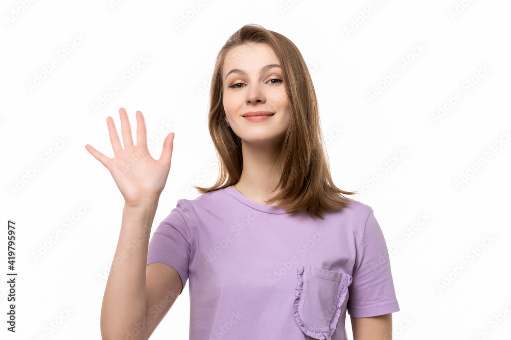 close up friendly girl saying hello, smiling joyfully and friendly, waving her hand, showing five fingers close up friendly girl saying hello, smiling joyfully and friendly, waving her hand, showing five fingers