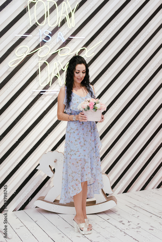Fototapeta premium slender brunette in a blue dress stands with a bouquet of flowers