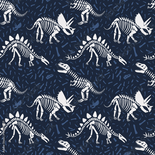 Dinosaurs skeletons seamless pattern on dark blue background with bones. Children textile with dinos skulls.