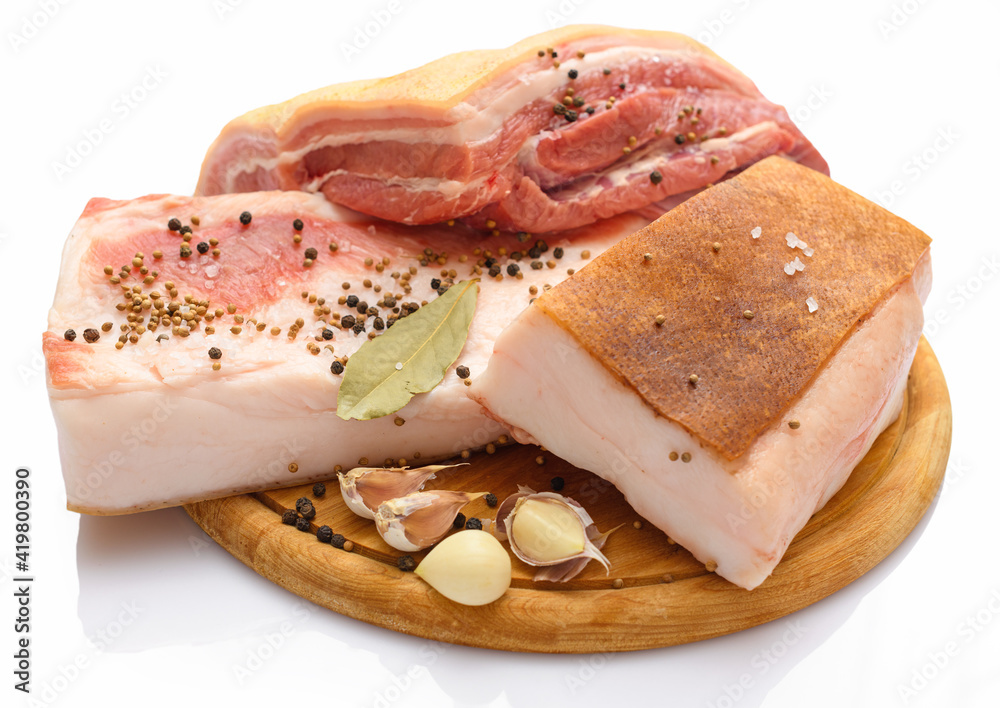 raw pork meat and lard with salt, spices and garlic on a cutting board, white background