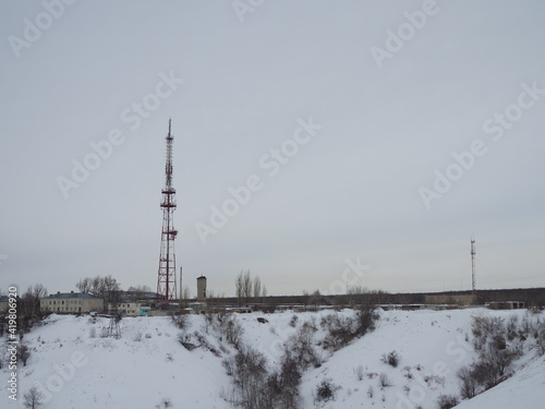 Snow-covered winding road leads to the radio tower with cellular phone in winter, near the village in the north of the Arctic Circle