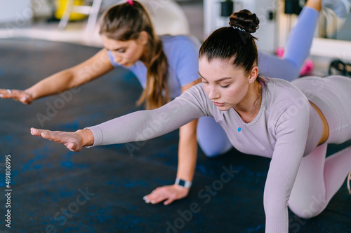 Young women doing push-ups workout fitness posture bodybuilding exercise at fitness studio. Fitness, sport, people and healthy lifestyle concept. Female making yoga in balancing table pose at gym.