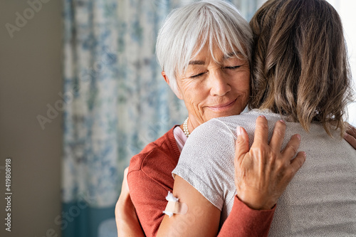 Senior woman embracing daughter after covid immunization vaccine