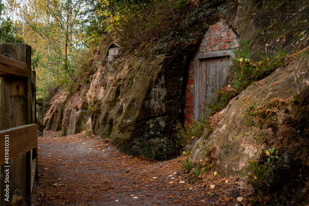 Cellar cliffs in Cave Rock (Lustuzis) in Ligatne, Latvia during cloudy autumn day that were used for storage of goods Cellar cliffs in Cave Rock (Lustuzis) in Ligatne, Latvia during cloudy autumn day that were used for storage of goods