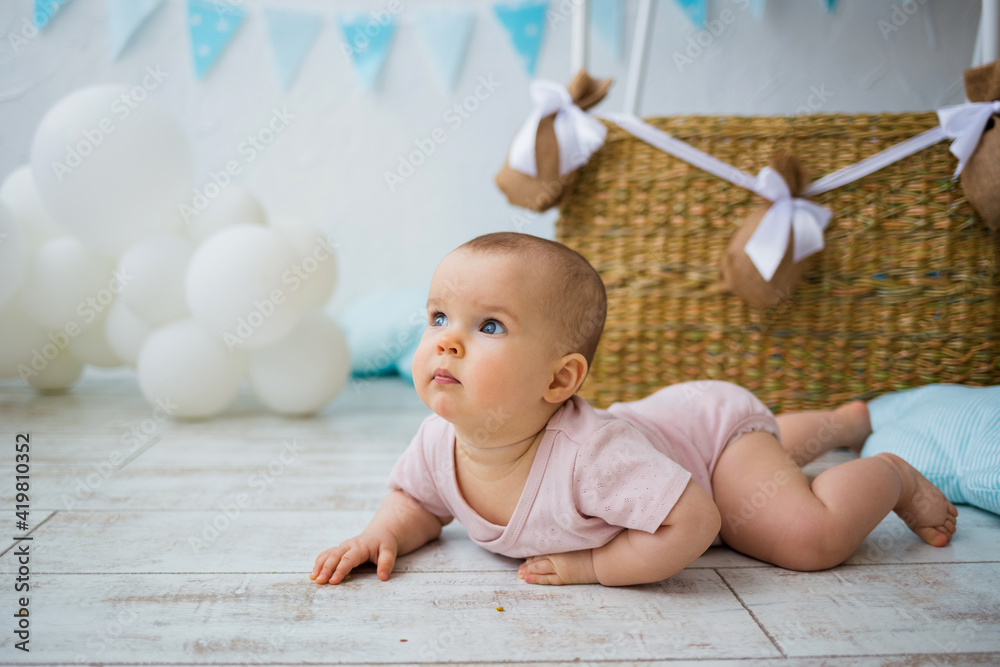 portrait of a baby crawling on the floor against the background of a wicker basket with balloons with space for text portrait of a baby crawling on the floor against the background of a wicker basket with balloons with space for text