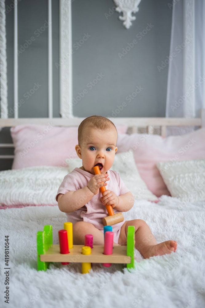 smart baby girl sitting on the bed with colorful educational toy smart baby girl sitting on the bed with colorful educational toy